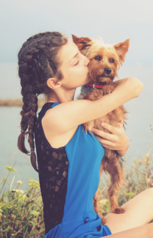Portrait d'une jeune fille qui embrasse son chien Yorkshire au bord de la mer