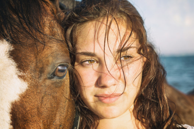 Portrait d'une jeune fille et son cheval jument en gros plan au bord de la mer